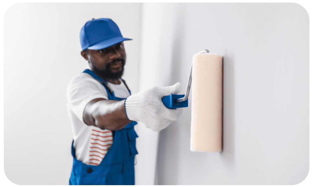 Homem negro com um pincel na mão pintando uma parede