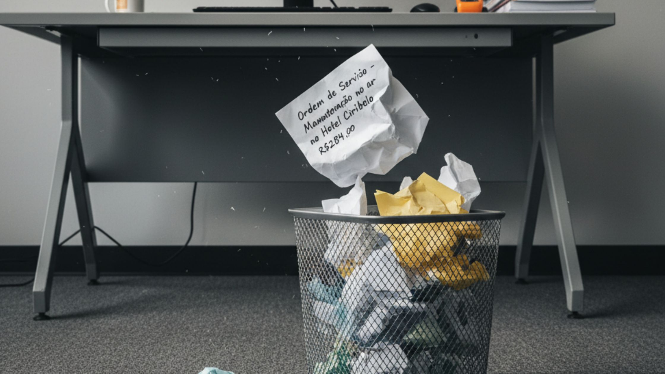 Ordem de serviço feita a mão sendo jogada no lixo, pois agora os chamados são registrados em um sistema de manutenção.