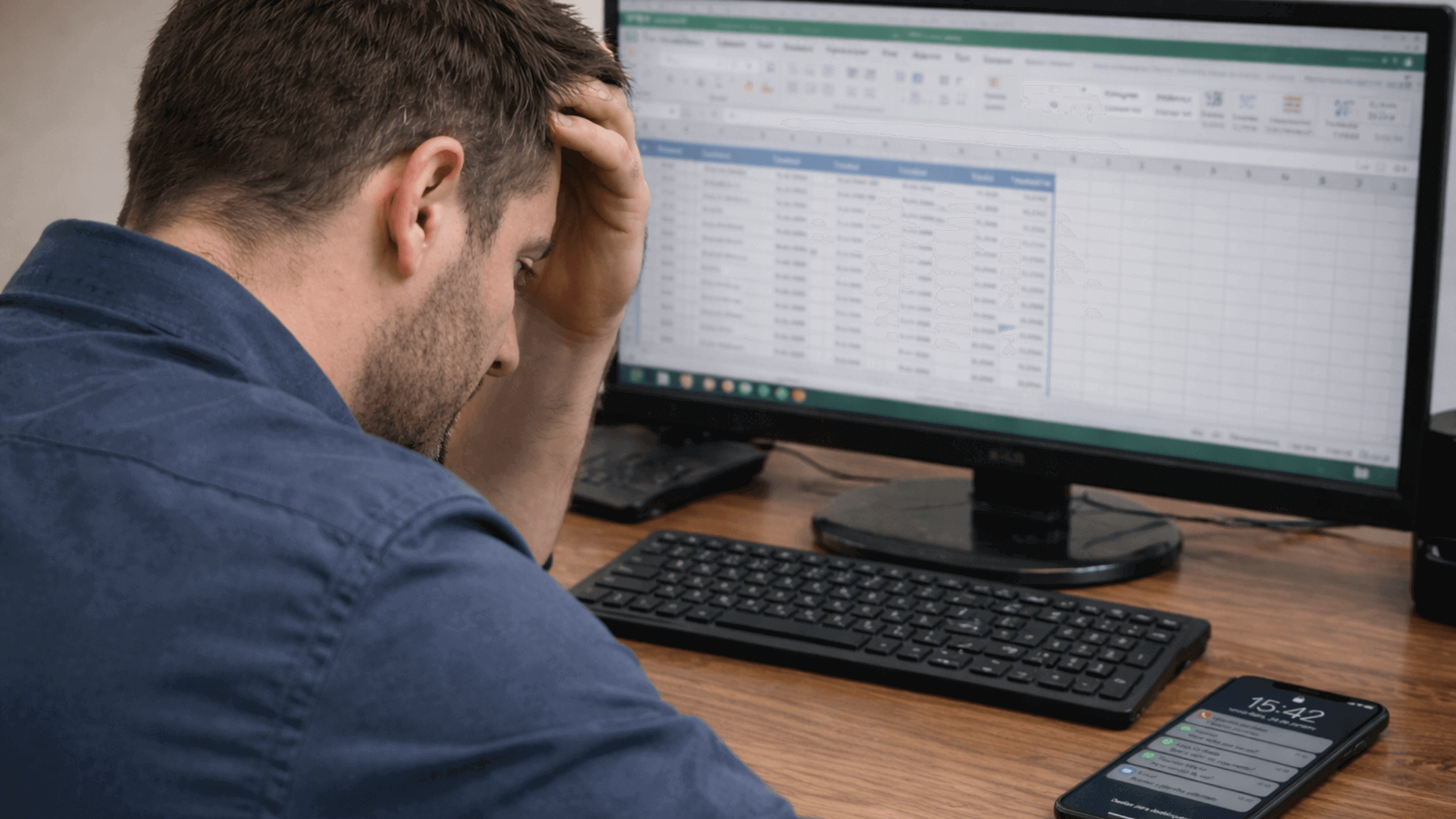 homem com a mão na cabeça preocupado ao olhar para planilha de manutenção